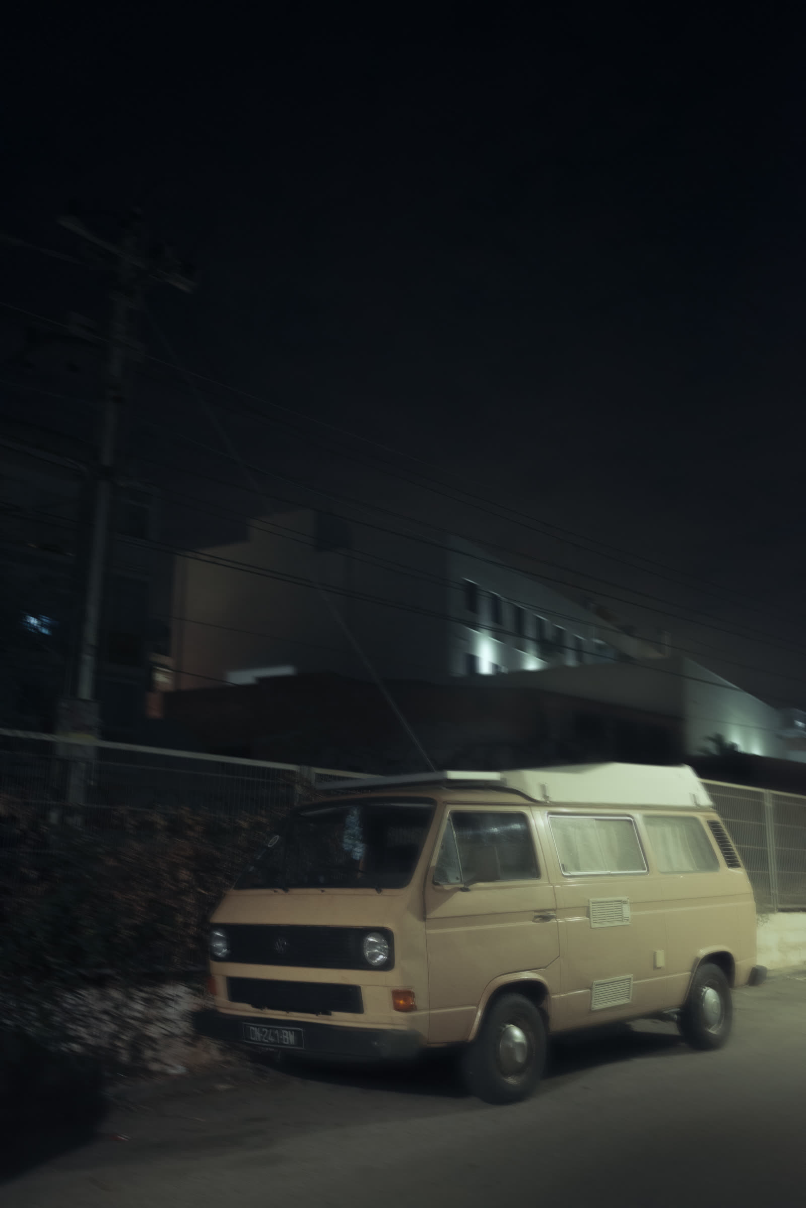 A vintage camper van parked for the night, the sky above streaked with motion blur