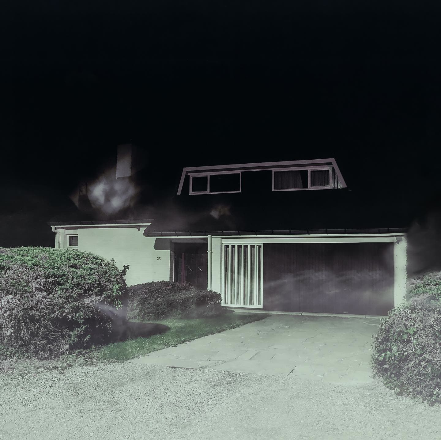 A brick house with two warm windows glowing under a darkening sky