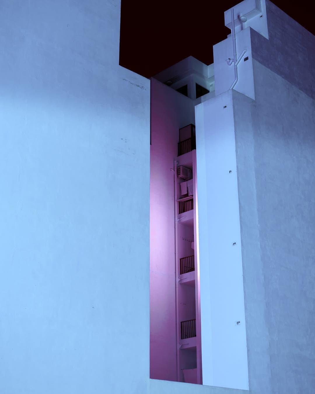Looking out through an open window onto a narrow courtyard, lit pink below